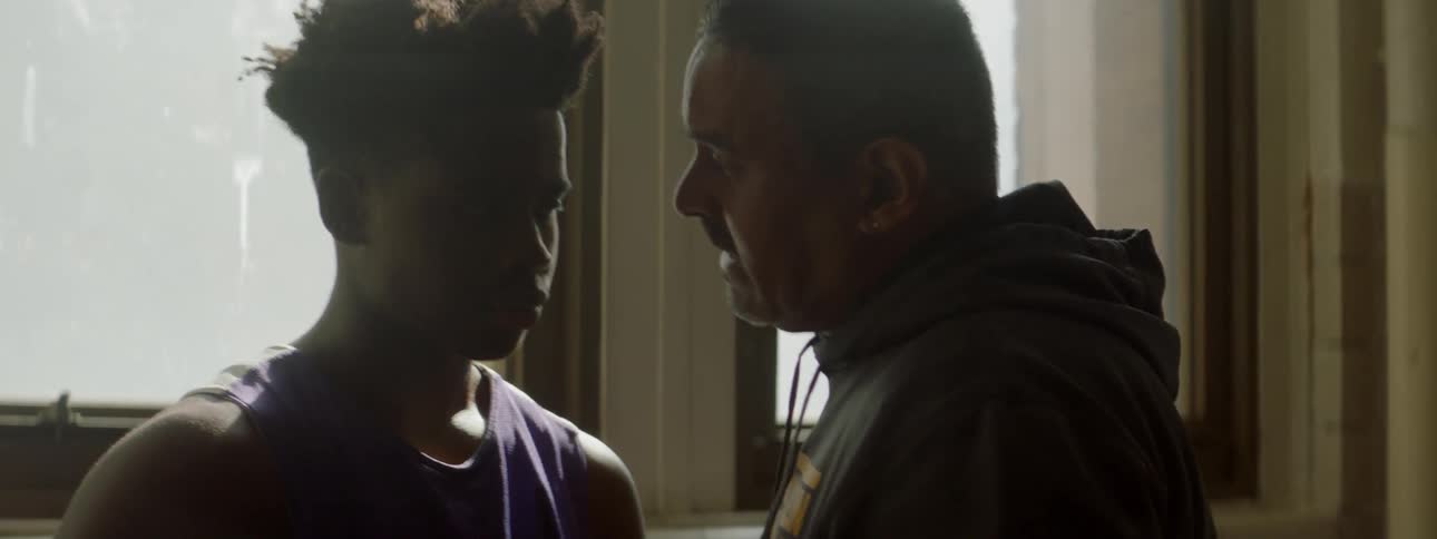 A man in a hoodie talks to a young man