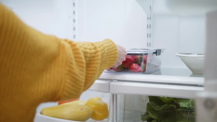 The view is of a young woman opening the fridge