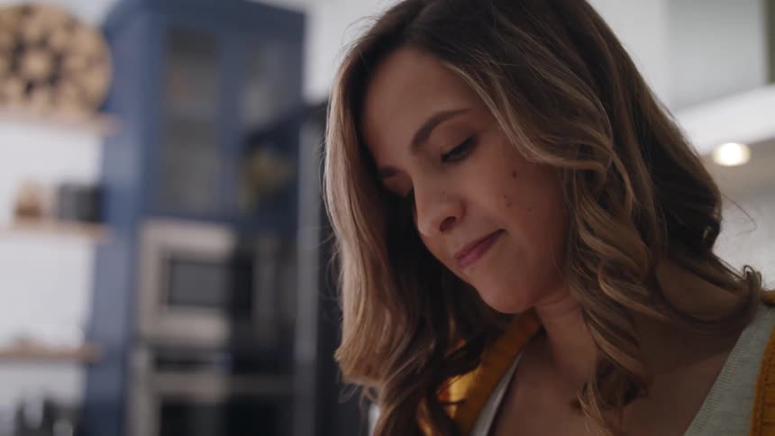 A teenage girl is standing in a room and looking down at what she is doing