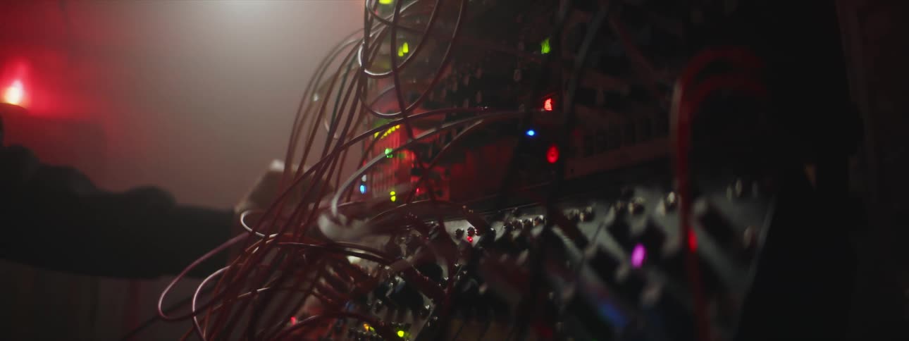Person wires electronic machine in dim room