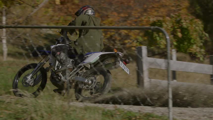 A man is riding his motor bike outdoors in the forest area