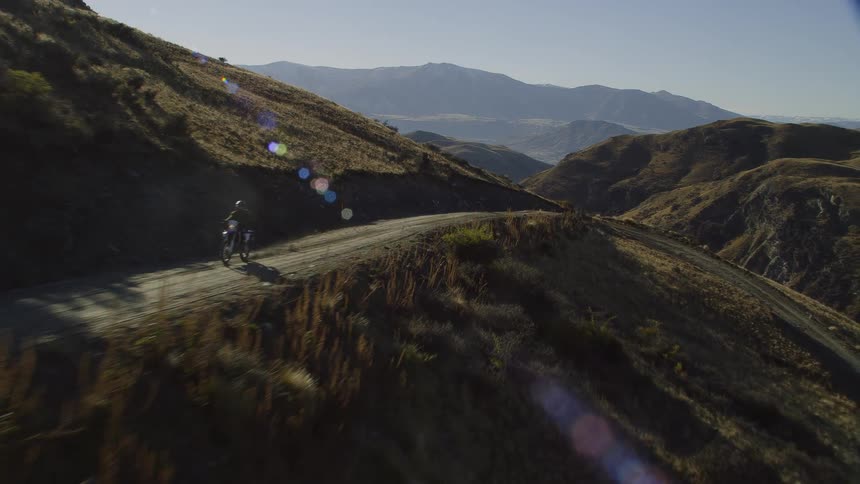 A person rides a dirt bike over the mountains