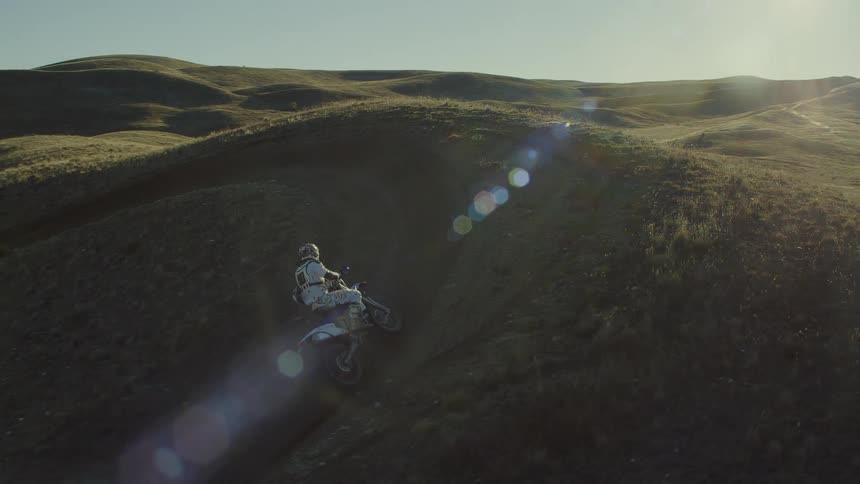 Person rides dirt bike in the hills