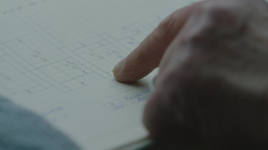 A man runs his finger along a blueprint