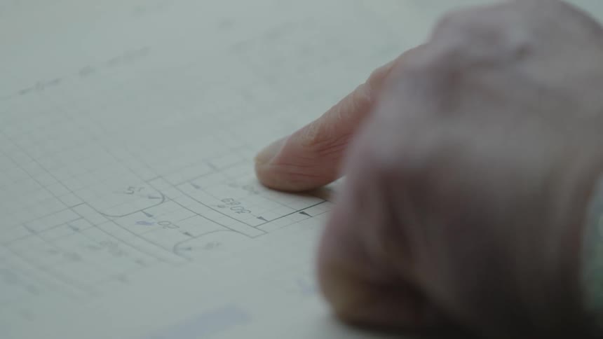 A man points at a blueprint