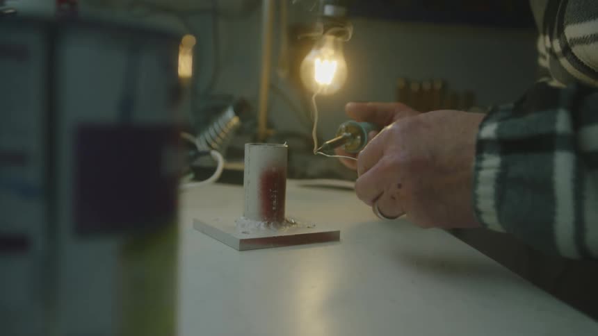 A close up of a persons hands while they hot iron metal together