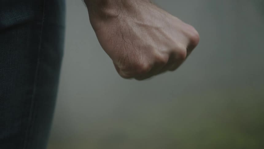 A close up of a mans hand as he stretches it makes a fist and then stretches it again