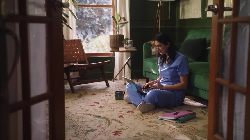 A young woman is sitting down and is on her laptop