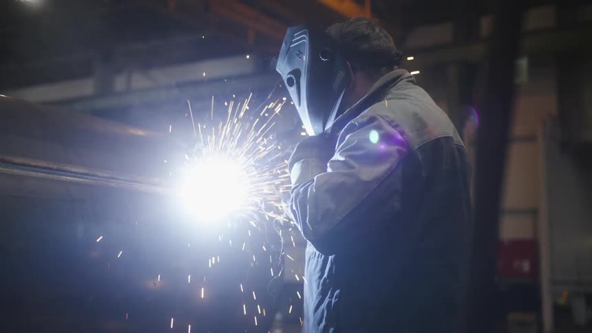 An older man is working inside of a building at a factory