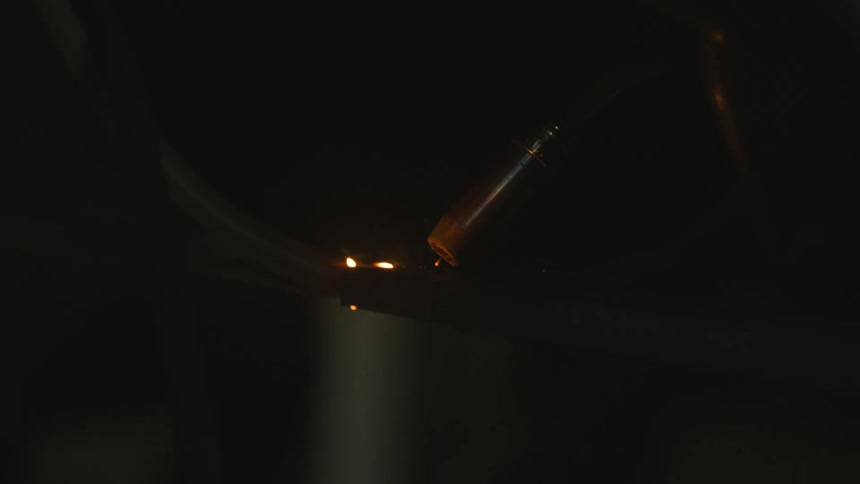 A welder is working as sparks glow and fly from a bright flare of light