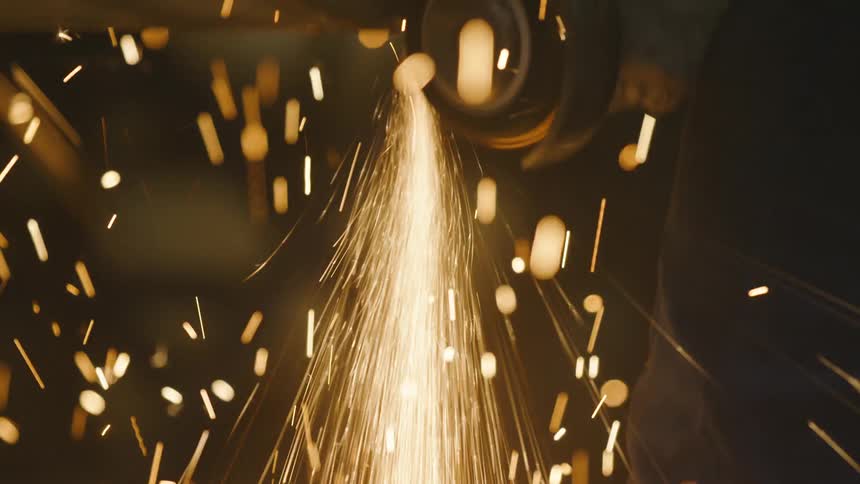 Close up of sparks falling on the ground from a power tool cutting metal