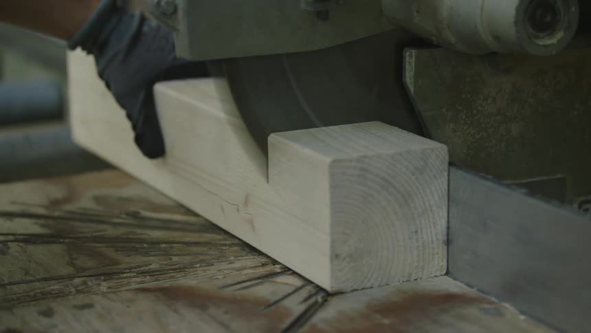 A carpenter cutting a piece of wood with a power saw
