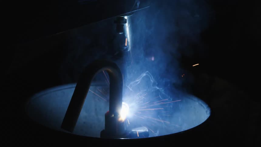 Sparks fly into dark area while joint inside cylinder is welded