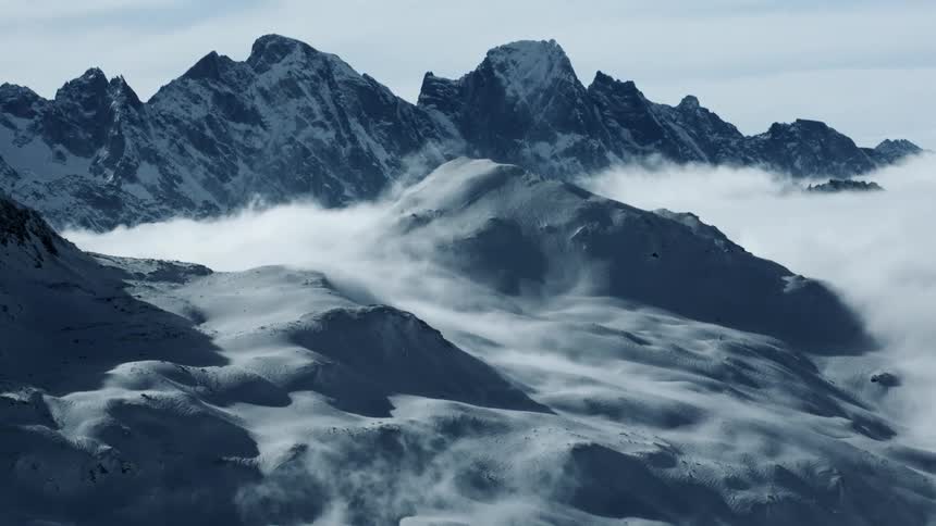 Majestic Peaks: Snow-Covered St. Moritz Mountains Towering Above the Clouds