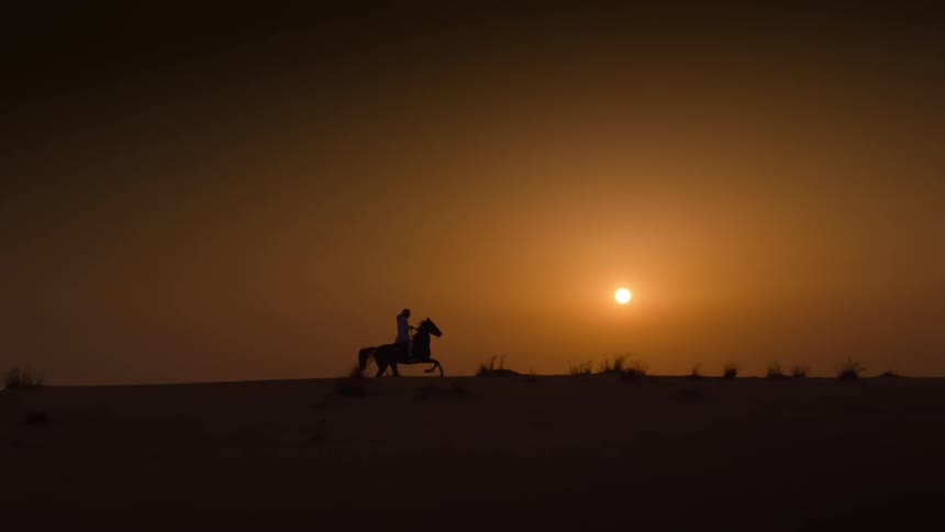 Silhouette of a person riding a horse at sunsets golden hour near a yellow bright sun