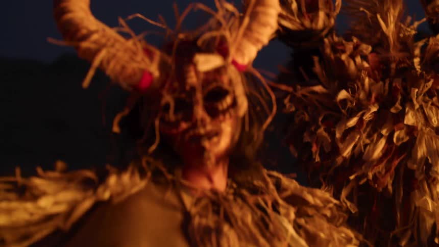 A group of people dressed in costumes and head dresses dancing around at night
