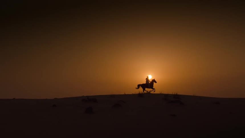A person is riding a horse at sunset