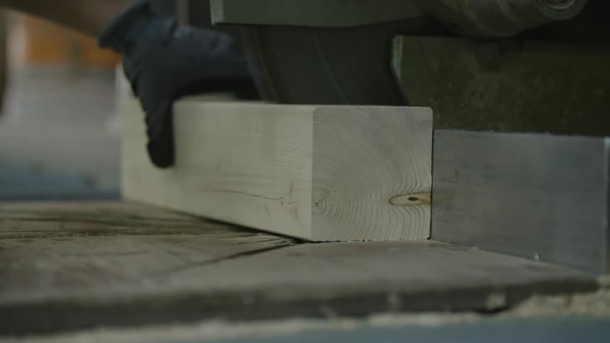 A person is cutting lumber with a table saw