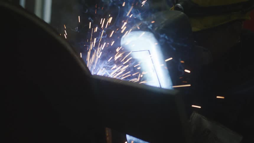 A person welding metal and creating sparks while wearing protective equipment