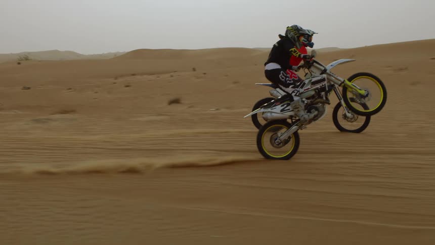 Two people are racing on dirt bikes in the desert