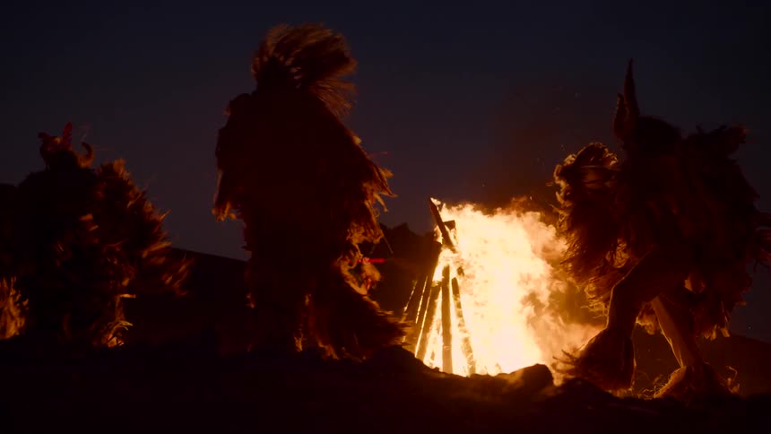 The view is people dancing around a fire outside at night
