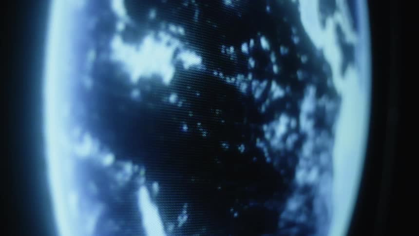 A holographic globe of the world glows as it turns in the darkness