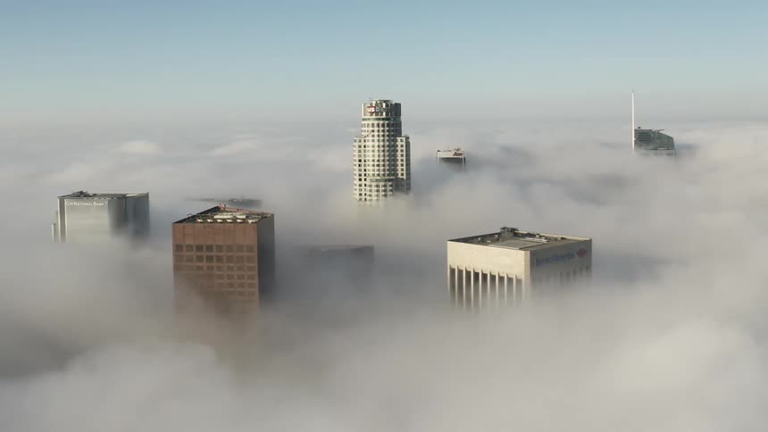 The tops of skyscrapers and towers stand above the clouds in the sky