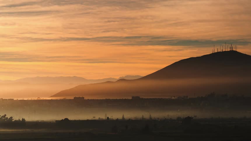 Landscape of distant city and mountain silhouetted against the sky at dawn