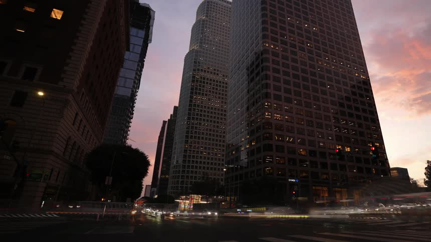 Traffic moves through downtown city streets under red tinted clouds