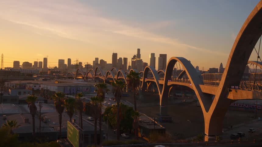 Car traveling over an urban bridge with arches at sunrise