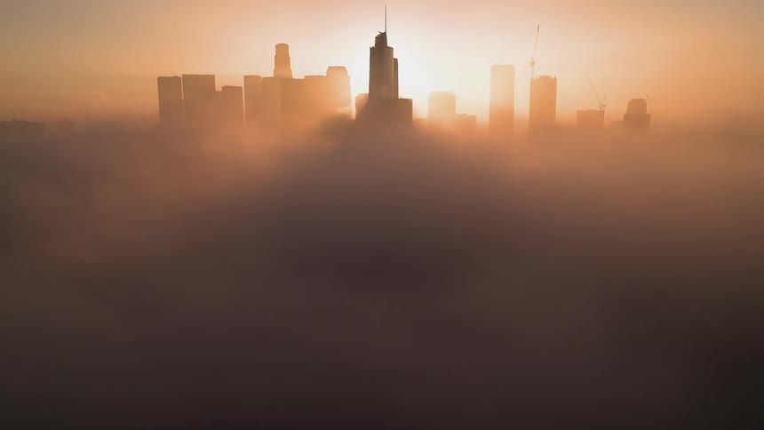The sun rises over downtown as dense clouds fill the sky