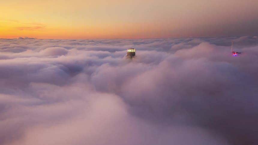 Dense clouds surround the top of tall skyscrapers