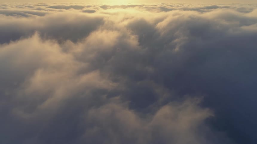 Moving over a cloudy sky as the sun glows in the distance