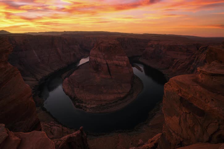 The sun sets over a canyon with a circular river