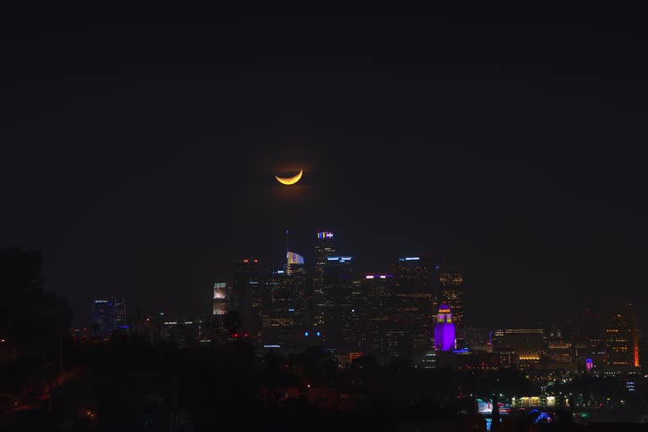Time lapse of moon going down behind the skyline at night