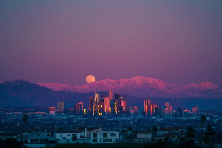 Time lapse of full moon going up behind the city skyline