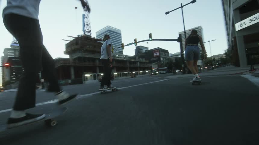 A group of skateboarders cross an intersection in a metropolis during the day