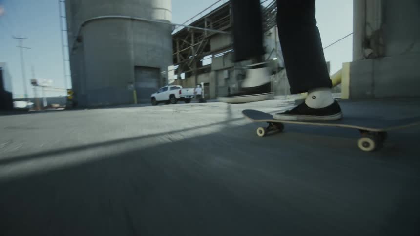 A group of teenagers skateboarding on a road near a factory in the city
