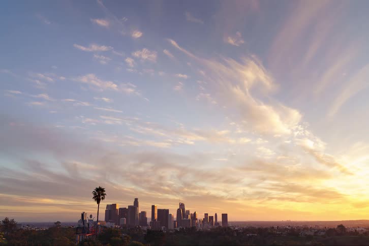 Clouds pass over the distant skyscrapers of a metropolis as the sunsets