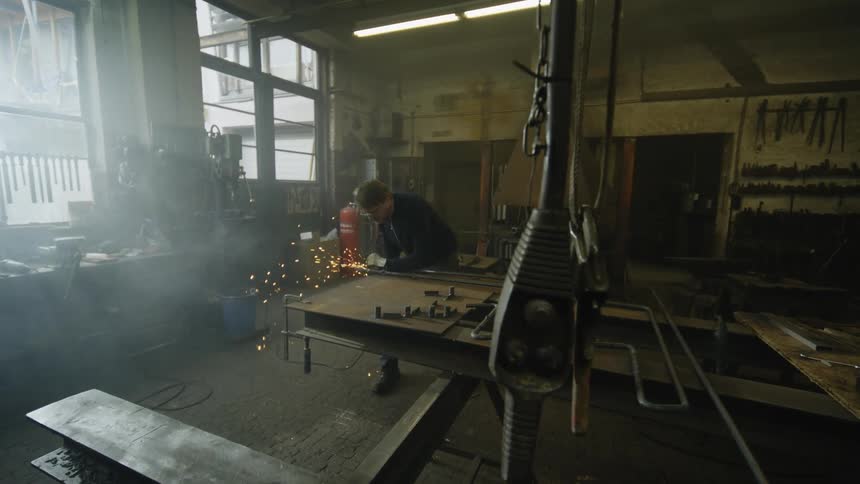 A man in a workshop using a tool creating sparks from metal