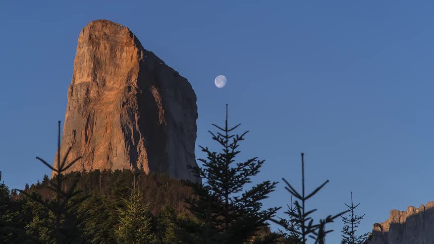 Time lapse footage of the moon setting over the mountains at sunrise