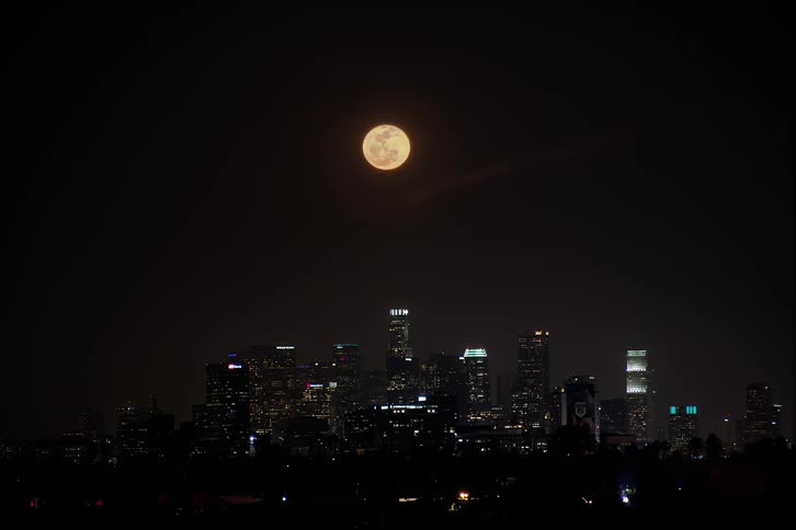 Time lapse of full moon rising over the skyline of the city at night