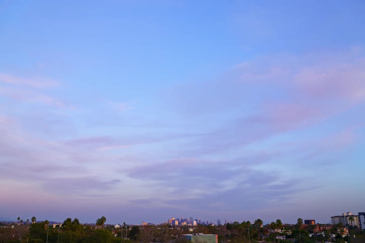 Clouds floating over buildings and skyscrapers in a city at sunset