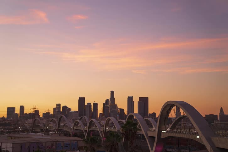 Traffic crosses bridge toward city downtown as the sun sets and night falls
