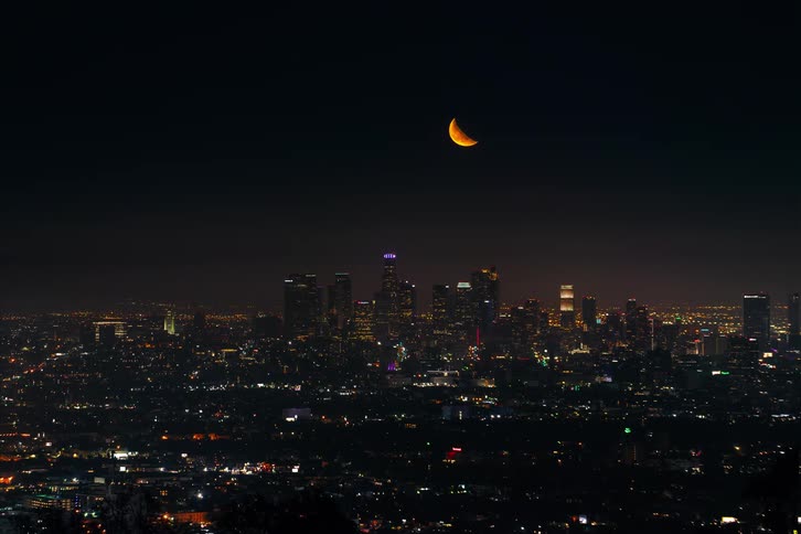 The moon rises over the city