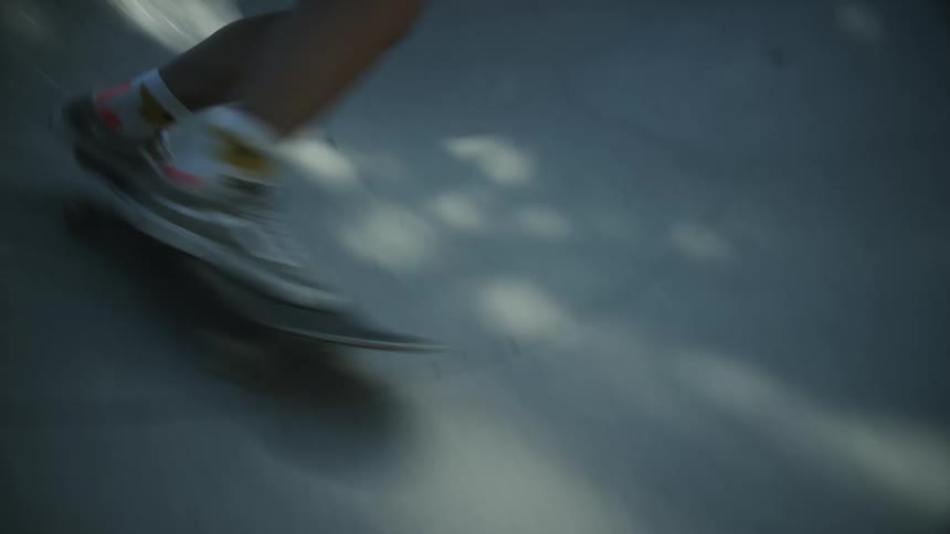 A dynamic handheld shot of a young female skater riding through a skatepark