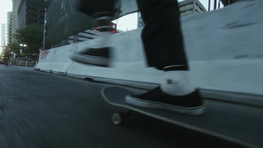 A skateboarder skates down a street in a metropolis during the day