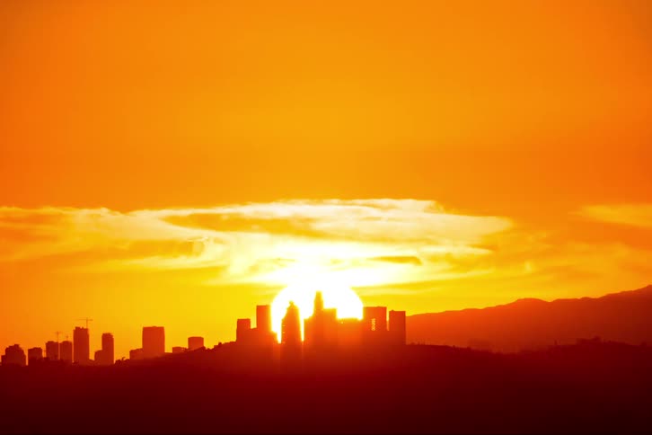 A time lapse of a bright sun setting behind a silhouette of a city