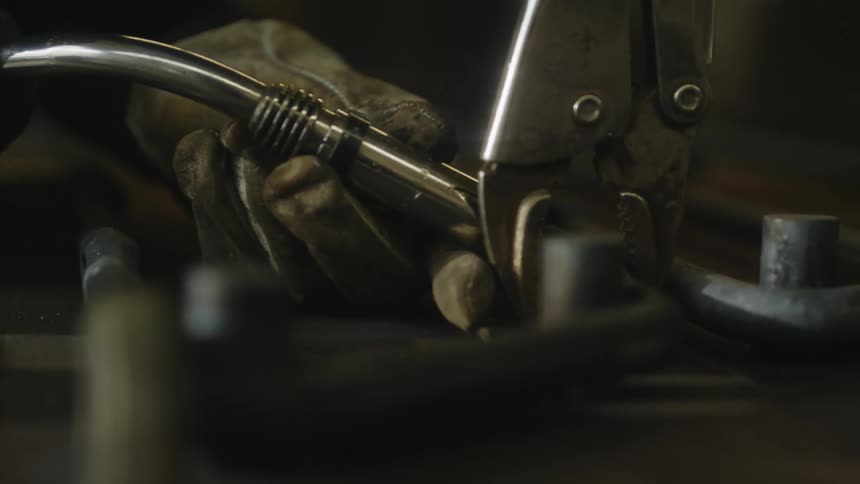 Welder wearing gloves uses welding torch on metal joint
