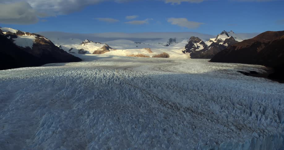 An aerial view of a land of glaciers in winter with mountain ranges all around with snow covered peaks